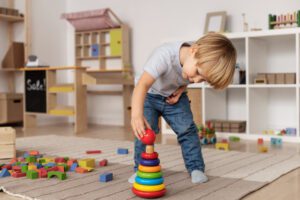 garoto de tiro completo brincando no chao com brinquedo de madeira Crianças autistas: falhas nos atendimentos
